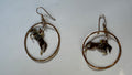 Pair of earrings with circular gold frames and horse figures on a white background